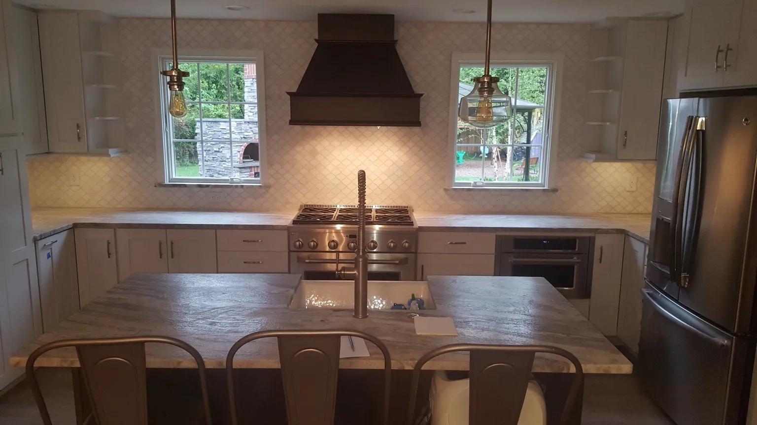 Custom kitchen with professional range, large island, built-in cabinetry, and pendant lighting